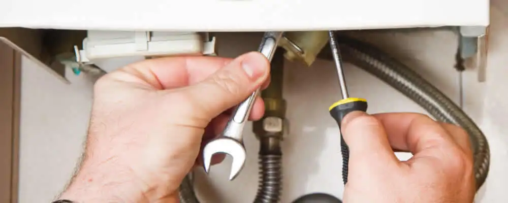 Boiler repair technician tightening pipe fittings and connections in Kenosha, WI