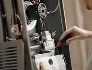 Furnace repair technician inspecting internal components and wiring in Kenosha, WI