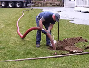 Septic pumping technician servicing a residential septic tank with a vacuum hose in Kenosha, WI