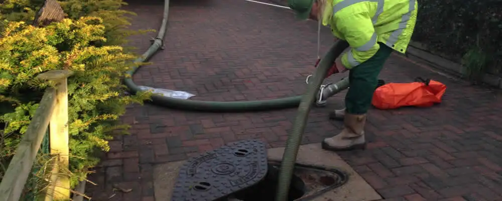 Septic tank cleaning technician servicing a septic tank with a vacuum hose in Kenosha, WI