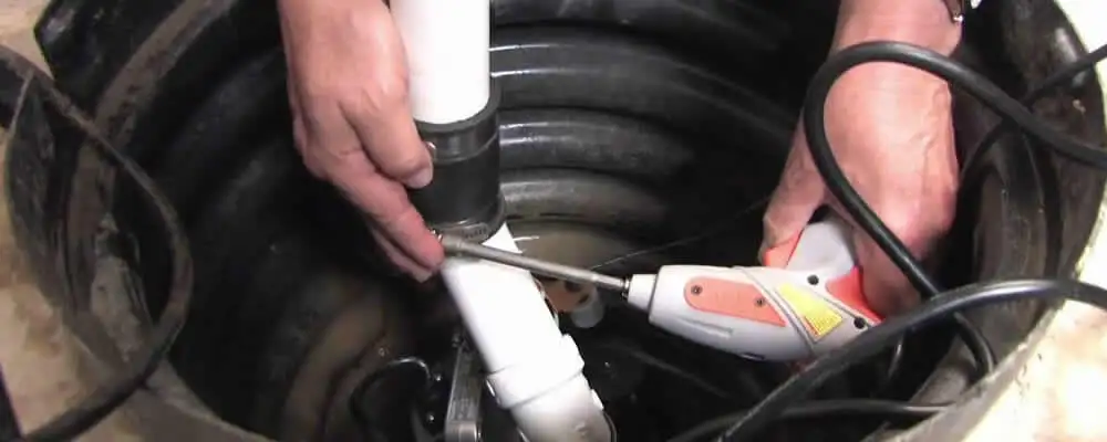 Sump pump installation technician connecting PVC discharge piping in Kenosha, WI