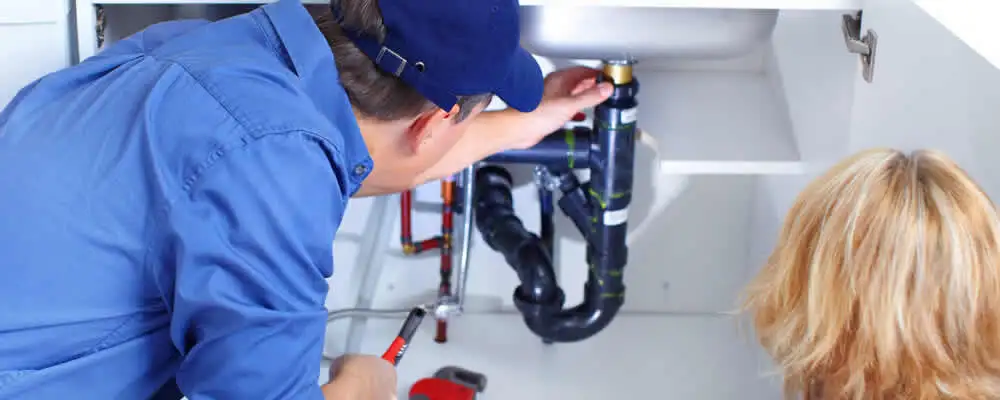 Plumber repairing under-sink drain pipes and fittings in Kenosha, WI